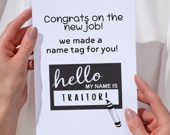 May include: A white greeting card with the text "Congrats on the new job!" and "we made a name tag for you!". The card features a black name tag that says "hello MY NAME IS TRAITOR!" with a marker illustration.