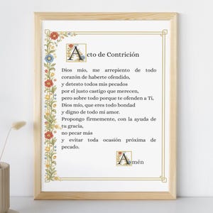Op de afbeelding: Een ingelijste print met de Spaanse tekst "Acto de Contrición". De tekst is zwart, met een decoratieve bloemenrand in rood, blauw en geel. De lijst is lichtbruin.