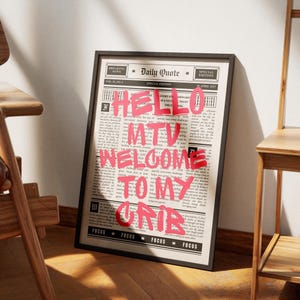 Könnte beinhalten: Gerahmter Druck mit Zeitungshintergrund und dem pinkfarbenen Text "HELLO MTV WELCOME TO MY CRIB". Der schwarz gerahmte Druck lehnt an einer Wand.