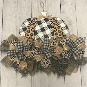 May include: A black and white checkered pumpkin with leopard print accents is decorated with black and white checkered and leopard print bows and brown burlap mesh.