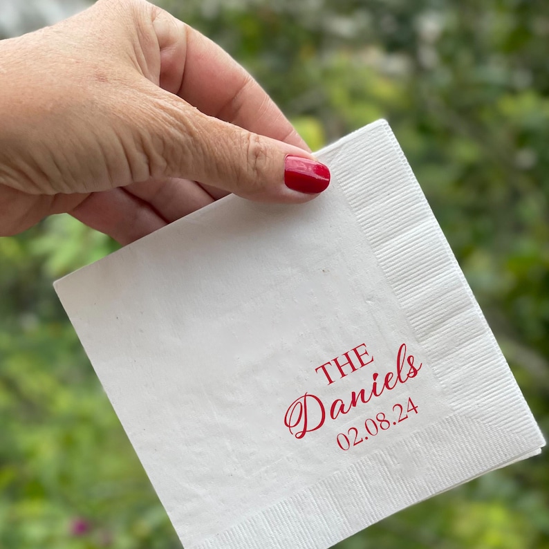 May include: White paper napkin with red text that reads "THE Daniels 02.08.24".