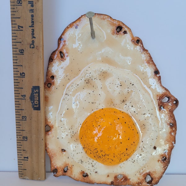 Fried egg hanging on a nail sculpture