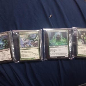May include: Four Magic: The Gathering trading cards in clear plastic sleeves arranged horizontally. The cards are Kokusho's Faithful, Elvish Skysweeper, Llanowar Visionary, and Viridian Acolyte, each featuring detailed fantasy character illustrations.