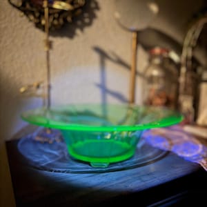 May include: A bright green glass bowl with a wide rim and a fluted design. The bowl is sitting on a dark wooden surface.