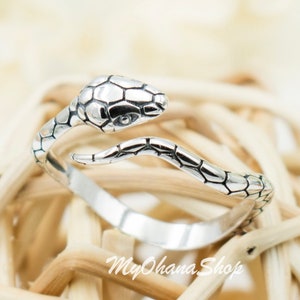 Op de afbeelding: Een zilveren slangenring met een gedetailleerd ontwerp. De ring is verstelbaar en kan aan elke vinger worden gedragen.