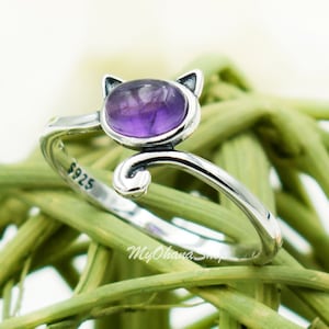 May include: A silver cat ring with a purple amethyst gemstone. The ring is marked with "925" on the band.