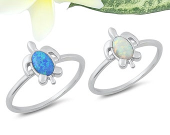 May include: Two silver rings with a turtle design. One ring has a blue opal stone and the other has a white opal stone.