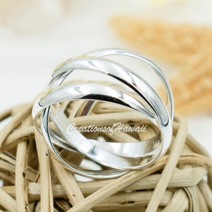 May include: A silver ring with a unique design featuring four bands that intertwine. The ring is made of sterling silver and has a polished finish.