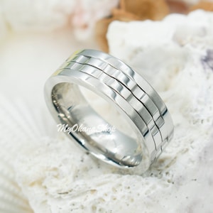 Peut inclure: Une bague en argent avec une bande texturée. La bande est composée de trois rangées de petits carrés.