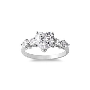 Op de afbeelding: Een zilveren ring met een grote, hartvormige, heldere steen en kleinere heldere stenen op de band.