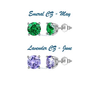 May include: Two pairs of silver stud earrings with round cubic zirconia stones. The top pair features emerald green stones and the bottom pair features lavender stones. The text "Emerald CZ - May" and "Lavender CZ - June" is displayed above each pair of earrings.