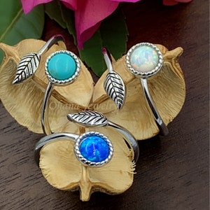 May include: Three silver rings with leaf accents and different colored stones. The stones are turquoise, white opal, and blue opal.