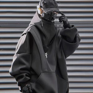 Puede incluir: Una persona con una sudadera negra con un bolsillo delantero grande, una gorra negra y una mascarilla. La sudadera tiene un gráfico blanco en el pecho. La persona también lleva guantes negros y tiene auriculares.
