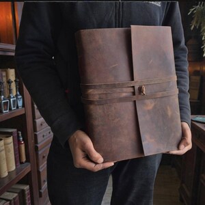 Handmade leatherbound journal with wrap strap, dark leather and deckle-edge pages; versatile grimoire for travel diary.