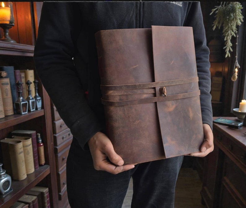 Handmade leatherbound journal with wrap strap, dark leather and deckle-edge pages; versatile grimoire for travel diary.