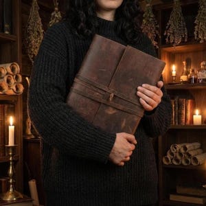 Handmade leatherbound journal with wrap strap, dark leather and deckle-edge pages; versatile grimoire for travel diary.