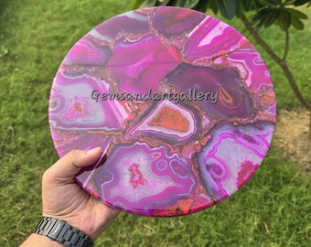 May include: A round, pink and white agate coaster with gold accents. The coaster is made of natural stone and has a unique, swirling pattern.