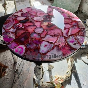 May include: A round table with a pink and purple agate stone top. The table has a black metal base.