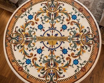 May include: A round stone table top featuring an intricate inlaid floral pattern in shades of blue, green, orange, and brown on a cream background. The center displays the text GemsAndArtGallery. The border consists of a brown and cream rope design.