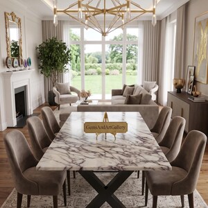 Puede incluir: Una mesa de comedor rectangular con tablero de mármol blanco veteado en morado y base de metal negro en forma de X. Un letrero dorado sobre un soporte se encuentra en la mesa, mostrando el texto GemsAndArtGallery en fuente serif. Seis sillas.