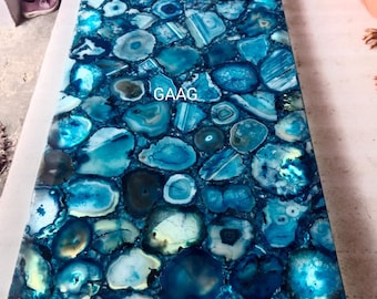 May include: A blue agate table top with a polished finish. The table top is made of many small pieces of agate that have been cut and polished to create a unique and beautiful design. The agate is a natural stone that is known for its beauty and durability. The table top is perfect for a modern or contemporary home.