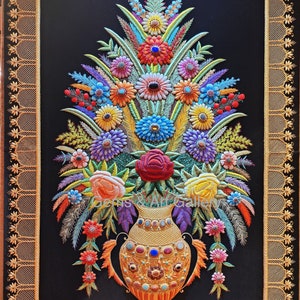 Puede incluir: Un arreglo floral bordado colorido en un jarrón dorado con joyas, sobre un fondo negro y enmarcado con un borde dorado.
