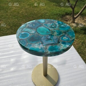 May include: A small, round side table with a teal and blue agate top. The table has a gold-colored base and a central support. The table is approximately 20 inches in diameter and 24 inches tall.