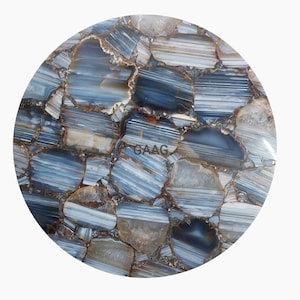 May include: A round, blue and brown agate table top with a natural, polished finish. The table top is made of many small pieces of agate that have been cut and polished to create a unique and beautiful design. The table top is perfect for a modern or contemporary home.