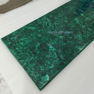 Puede incluir: Una losa grande y rectangular de malaquita verde con un patrón de mármol en espiral. La piedra está pulida y tiene una superficie lisa. El texto "Gemsandartgallery" es visible en el centro inferior de la losa.