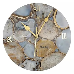 Può includere: Un orologio rotondo in agata bianco e oro con numeri romani. Il quadrante dell'orologio ha un aspetto testurizzato di pietra naturale.