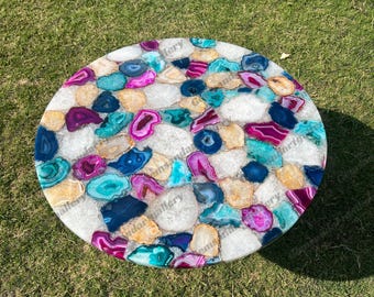 Könnte beinhalten: Eine runde Tischplatte mit einem Mosaik aus polierten Achat-Scheiben in leuchtenden Magenta-, Türkis- und Dunkelblautönen, durchsetzt mit durchscheinenden weißen Quarzfragmenten, die eine farbenfrohe, strukturierte Oberfläche bilden.
