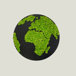 Op de afbeelding: Een zwarte ronde wanddecoratie met een groen mosontwerp van de aarde. De continenten zijn omlijnd met groen mos.
