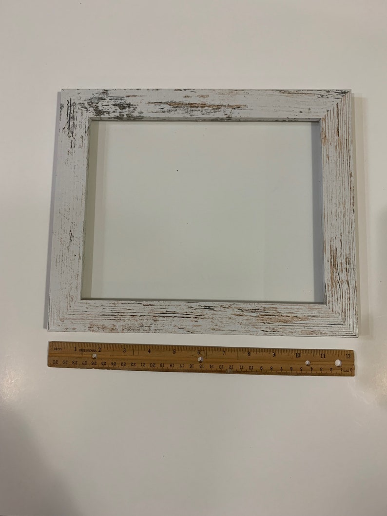 May include: White wooden picture frame with a distressed finish. The frame is 12 inches wide and 16 inches tall.