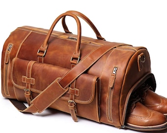 May include: A brown leather duffel bag with a shoulder strap and a zippered pocket on the side. The bag is open and has a pair of brown leather shoes inside.