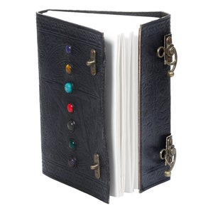 May include: Black leather journal with a pentagram design and colorful gemstones. The journal has two brass clasps and a decorative strap.