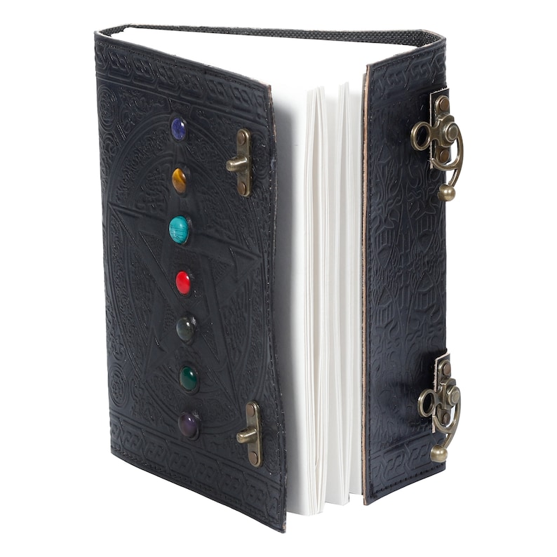 May include: Black leather journal with a pentagram design and colorful gemstones. The journal has two brass clasps and a decorative strap.