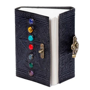 May include: A black leather journal with a pentagram design and a clasp closure. The journal has seven colorful gemstones embedded in the front cover.