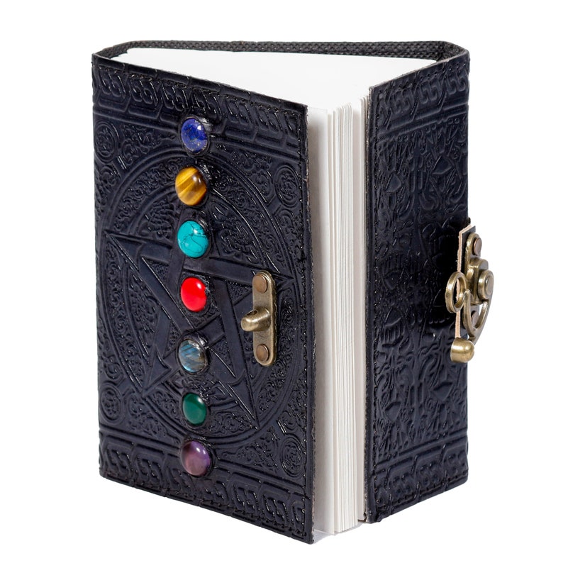 May include: A black leather journal with a pentagram design and a clasp closure. The journal has seven colorful gemstones embedded in the front cover.