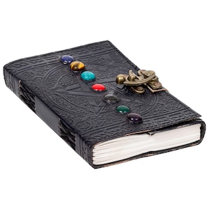 May include: Black leather journal with a pentacle design and a brass clasp. The journal is adorned with seven colorful gemstones.