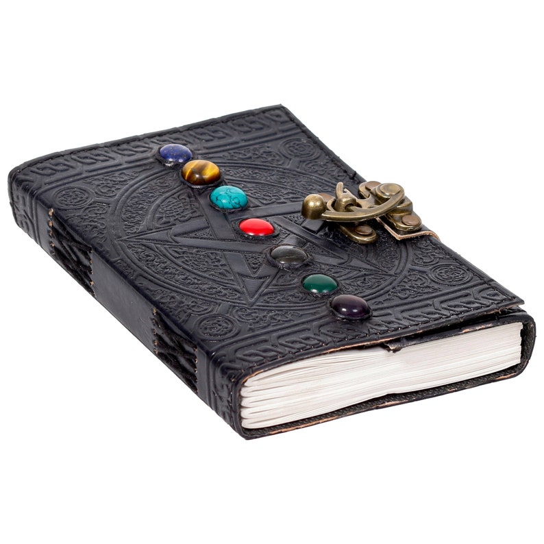 May include: Black leather journal with a pentacle design and a brass clasp. The journal is adorned with seven colorful gemstones.