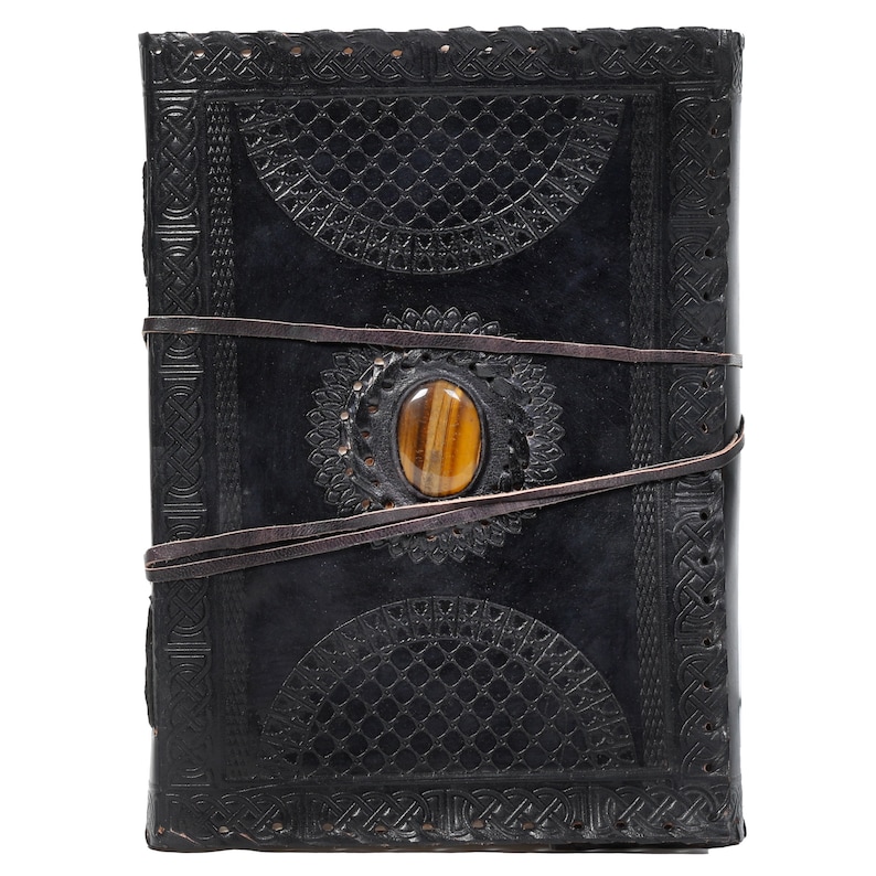 May include: Black leather journal with intricate embossed designs and a brown tiger's eye stone set in the front cover.