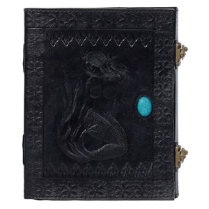 May include: Black leather journal with a mermaid embossed design and a turquoise stone inlay. The journal has two brass clasps.