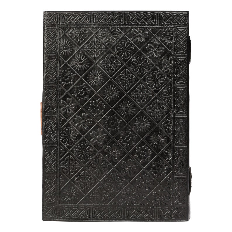 May include: Black leather journal with a decorative embossed pattern of flowers and geometric designs. The journal has a brown leather strap closure.