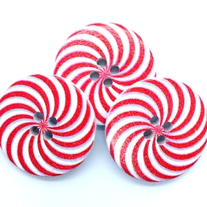 May include: Three wooden buttons with a red and white swirl pattern and three holes each.