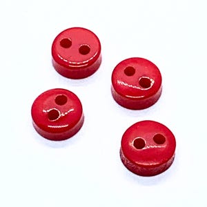 Peut inclure: Quatre boutons en plastique rouge avec deux trous chacun.