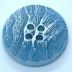 May include: A light blue button with a white textured design and four holes.