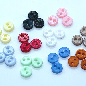 May include: Assortment of two-hole buttons in various colours, including black, white, red, blue, green, brown, and beige.