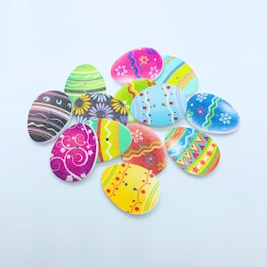 May include: Assortment of 12 wooden Easter egg-shaped buttons with various colourful designs and patterns. The buttons have a two-hole design and are perfect for crafting projects.