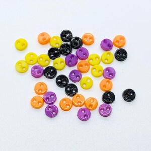May include: Assortment of small, two-hole buttons in black, orange, yellow, and purple.