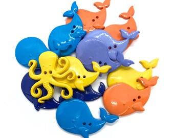 May include: A collection of colourful plastic buttons featuring ocean-themed designs. The buttons include whales, an octopus, and a starfish. The buttons are perfect for adding a whimsical touch to crafts and sewing projects.